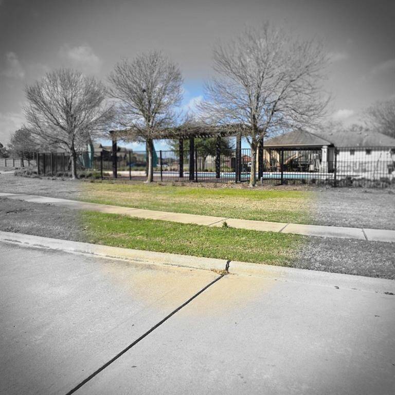 This photo shows a neighborhood with a fenced community area featuring a pool and gazebo, surrounded by trees and a sidewalk. The setting is peaceful, ideal for family living.