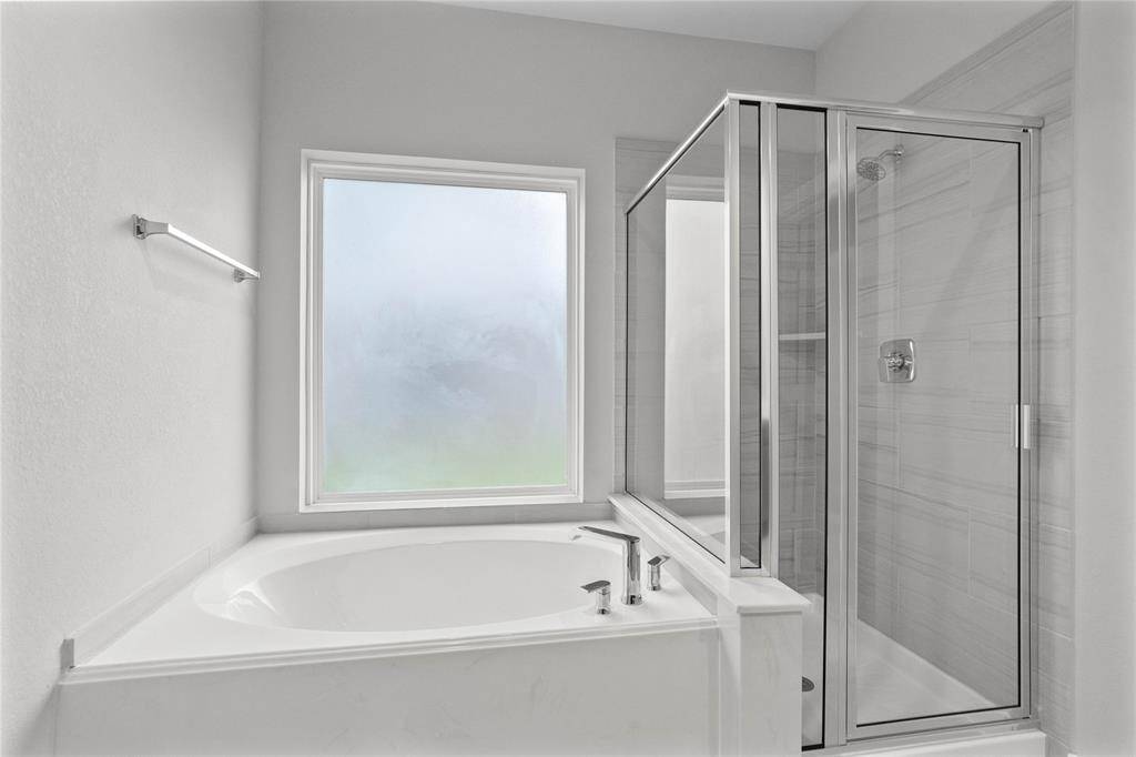 This primary bathroom is definitely move-in ready! Featuring dark framed walk-in shower with tile surround, separate garden tub for soaking after a long day with custom tile detailing, high ceilings, custom paint, sleek and dark modern finishes!