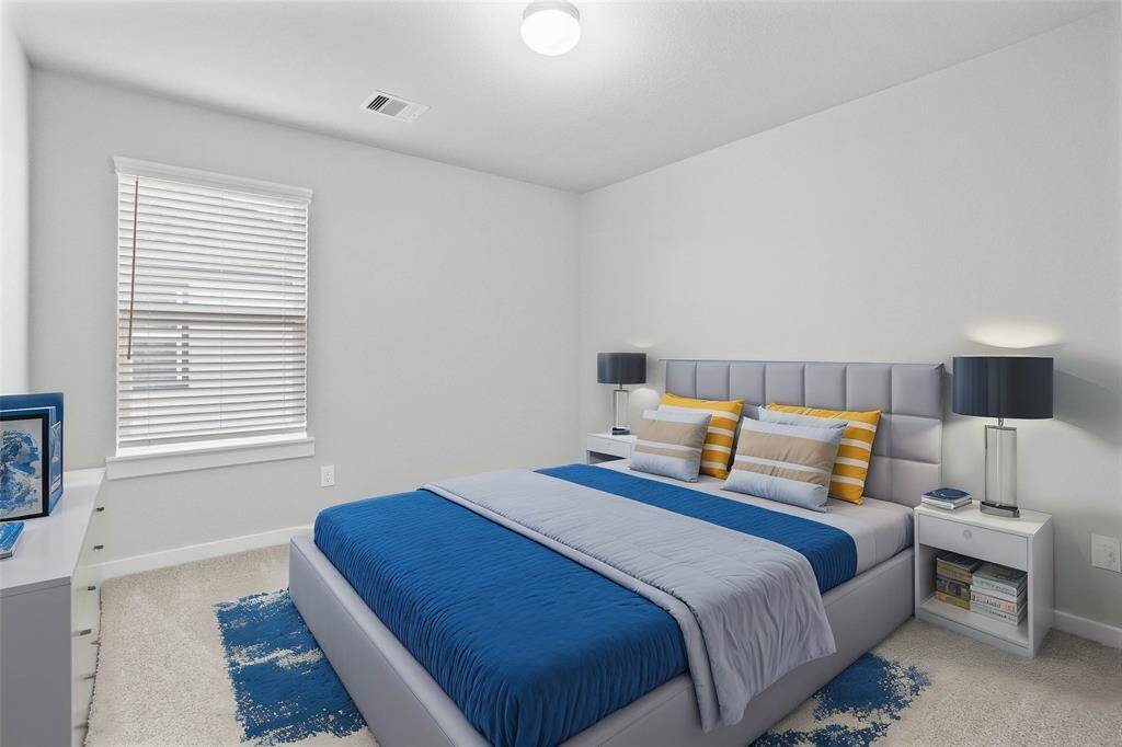 Secondary bedroom features plush carpet, custom paint, lighting, and a large window with privacy blinds.