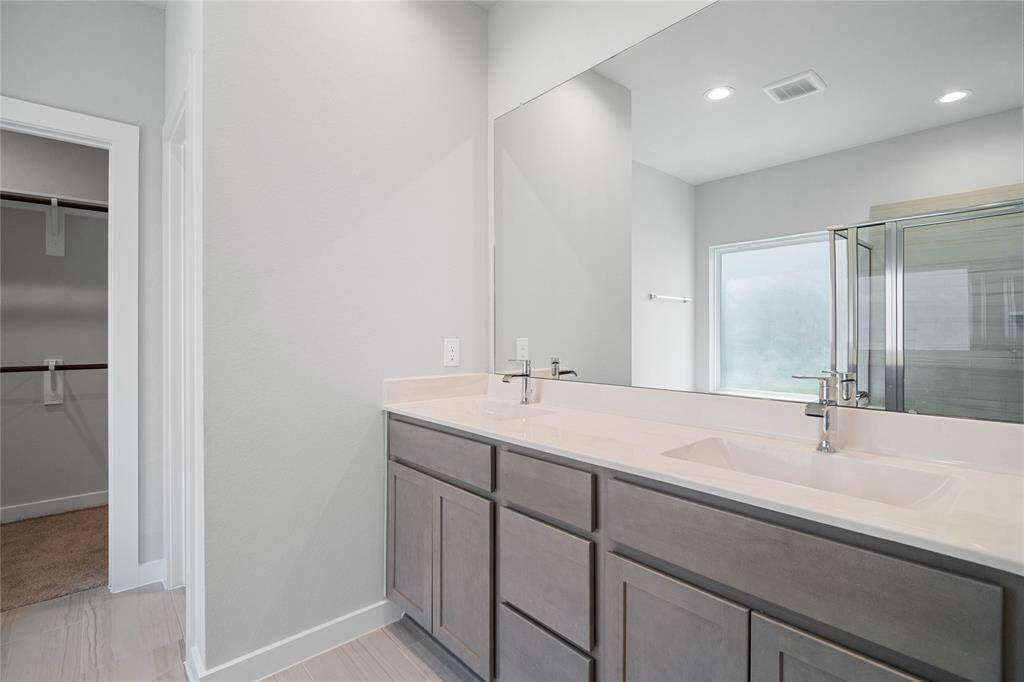 This primary bathroom is definitely move-in ready! Featuring stained cabinets with light countertops, spacious walk-in closet with shelving, high ceilings, custom paint, sleek modern finishes.