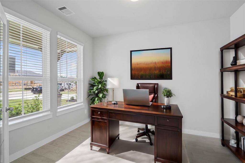 Quietly nestled in front of the home is the handsome home office. Featuring tile flooring, high ceilings, large windows with privacy blinds and custom paint.