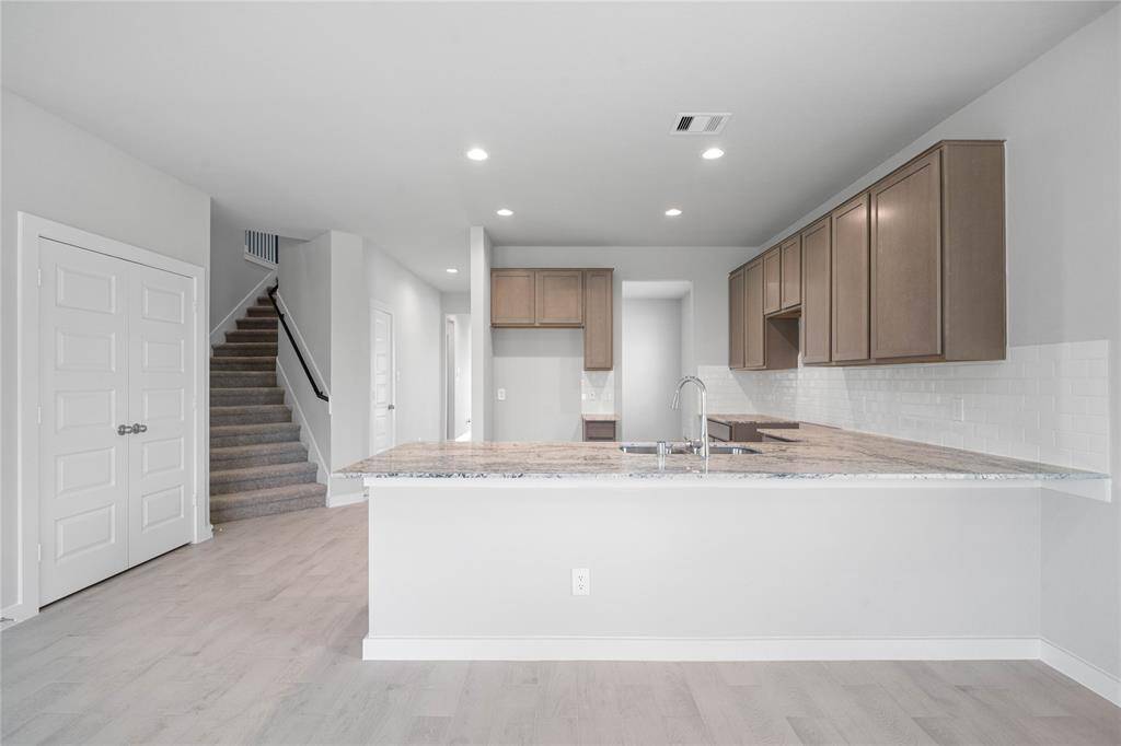 This kitchen is by far any chef’s dream! This spacious kitchen features high ceilings, stained wood cabinets, granite countertops, SS appliances, modern tile backsplash, recessed lighting, extended counter space for breakfast bar, and a walk-in pantry all overlooking your huge family room.