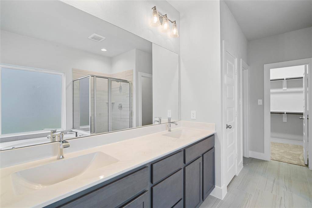 This primary bathroom is definitely move-in ready! Featuring stained cabinets with light countertops, spacious walk-in closet with shelving, high ceilings, custom paint, sleek and dark modern finishes.