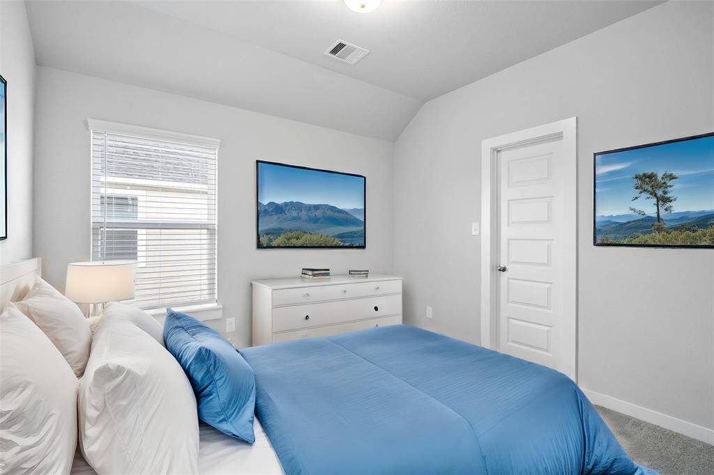 Secondary bedroom features plush carpet, custom paint and a large window with privacy blinds.