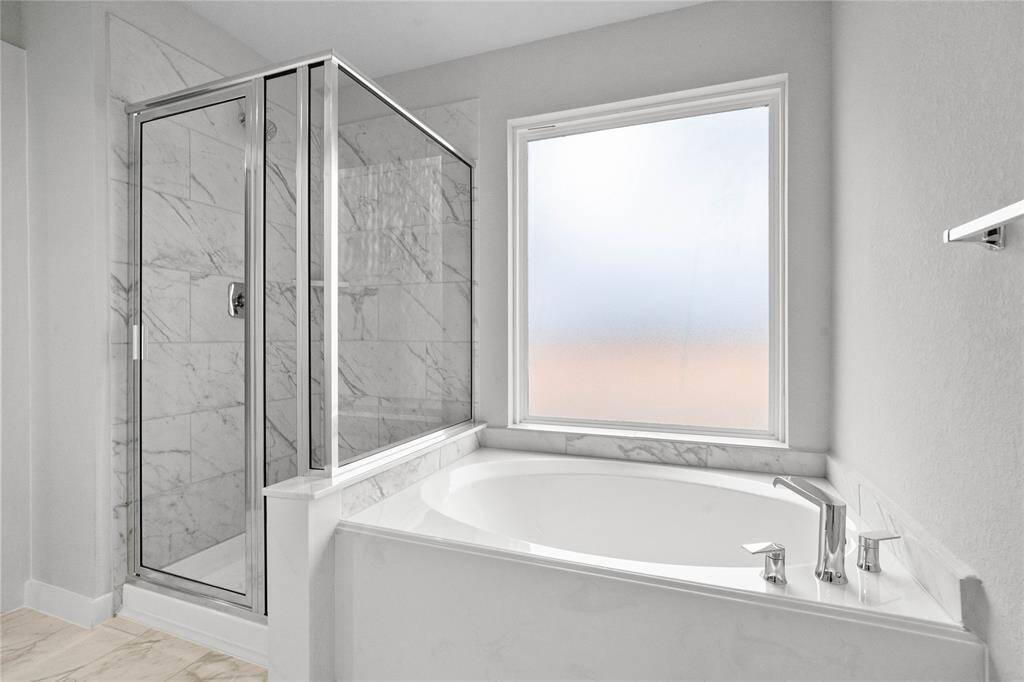 Additional view of the primary bathroom features dark framed walk-in shower with tile surround, and separate garden tub for soaking after a long day with custom tile detailing!