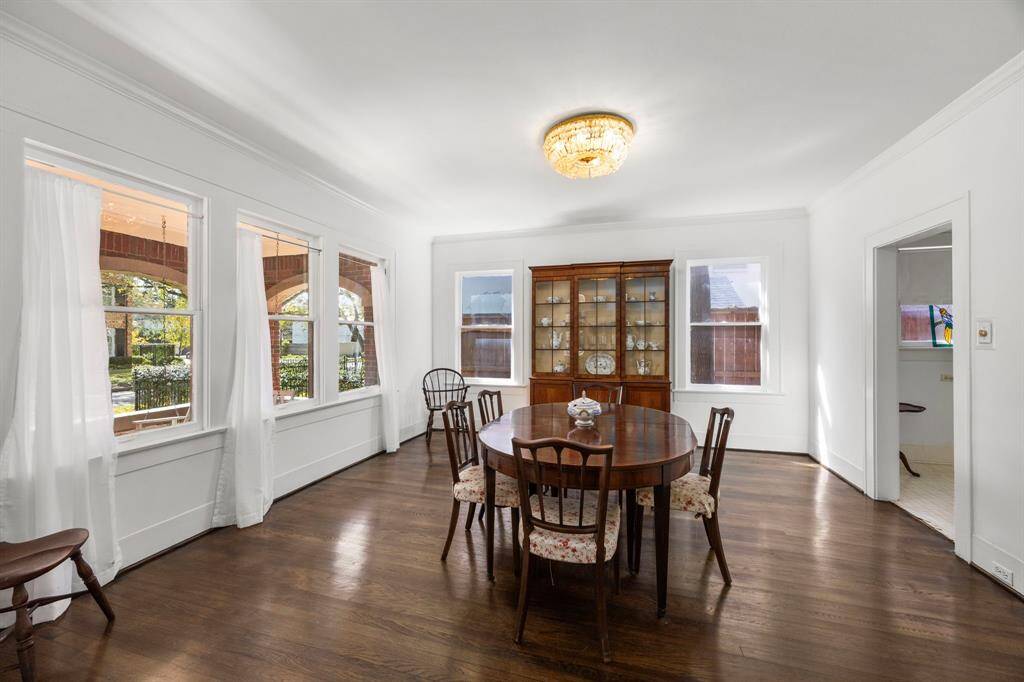 This spacious dining room features hardwood floors, a classic chandelier, and ample natural light from multiple windows.