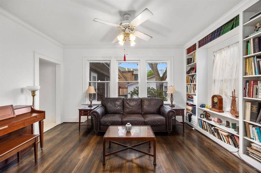 This inviting room boasts hardwood floors, a ceiling fan, and built-in bookshelves. Large windows flood the space with natural light, making it ideal for a cozy home office.