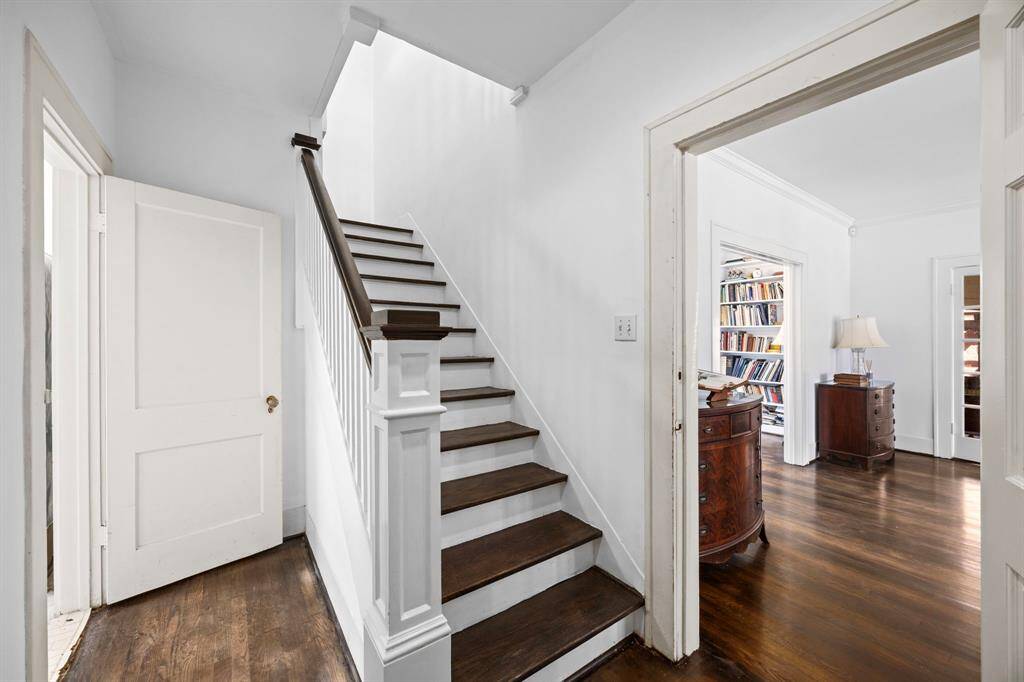 The stairs elegantly connect the living room and kitchen, with potential to create an open-concept space by removing the adjoining wall.