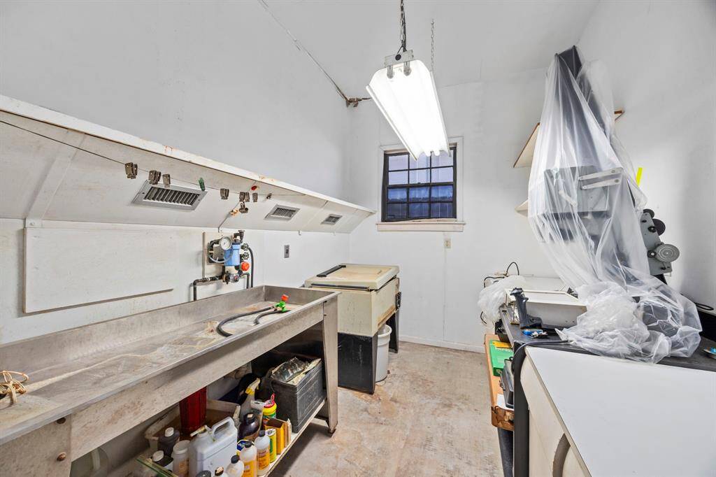Discover a versatile utility room featuring a large sink, generous counter space, and bright lighting with natural light from a window—perfect for laundry, a workshop, or pet grooming.