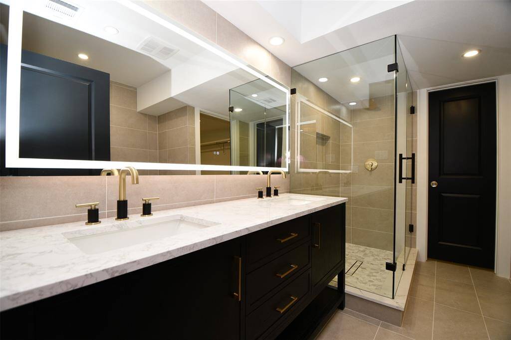 Primary bath features double sinks, oversized shower and a light mirror.