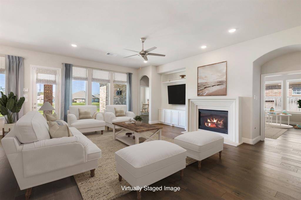 Spacious family room featuring wood floors, a cozy gas fireplace, built-ins, and direct access to the covered back patio. *Virtually Staged Image