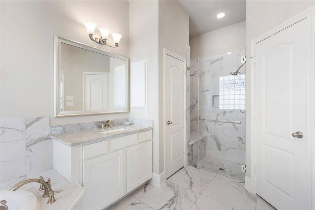 The elegance continues into the large walk-in shower with bench and shampoo niche.