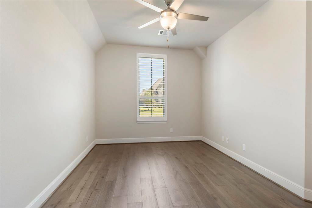One of 3 secondary bedrooms with wood flooring, elevated ceiling, plantation shutters and ceiling fan.