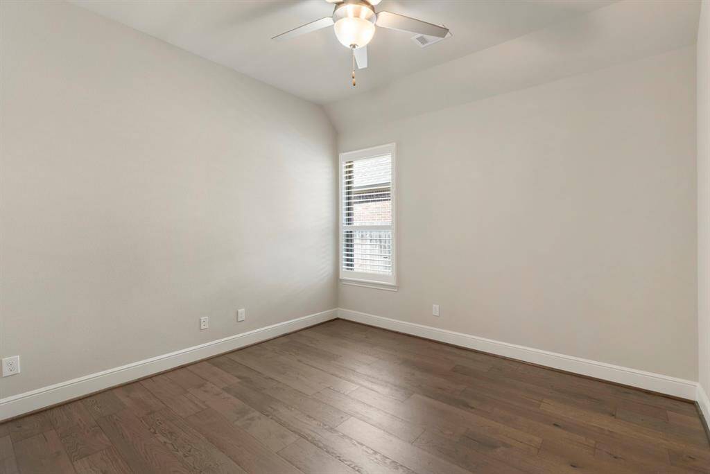 Secondary bedroom with wood floors, ceiling fan, shutters, and double door to closet.