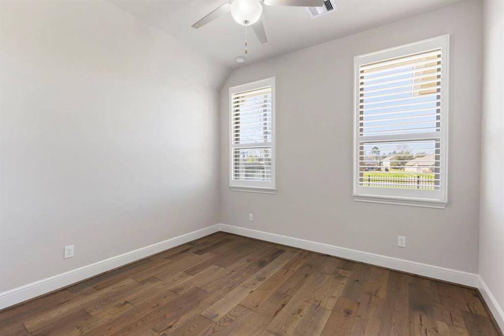 Generously sized bedroom 4 with wood flooring, ceiling fan, vaulted ceiling, large double windows with plantation shutters, and a private en-suite bath!