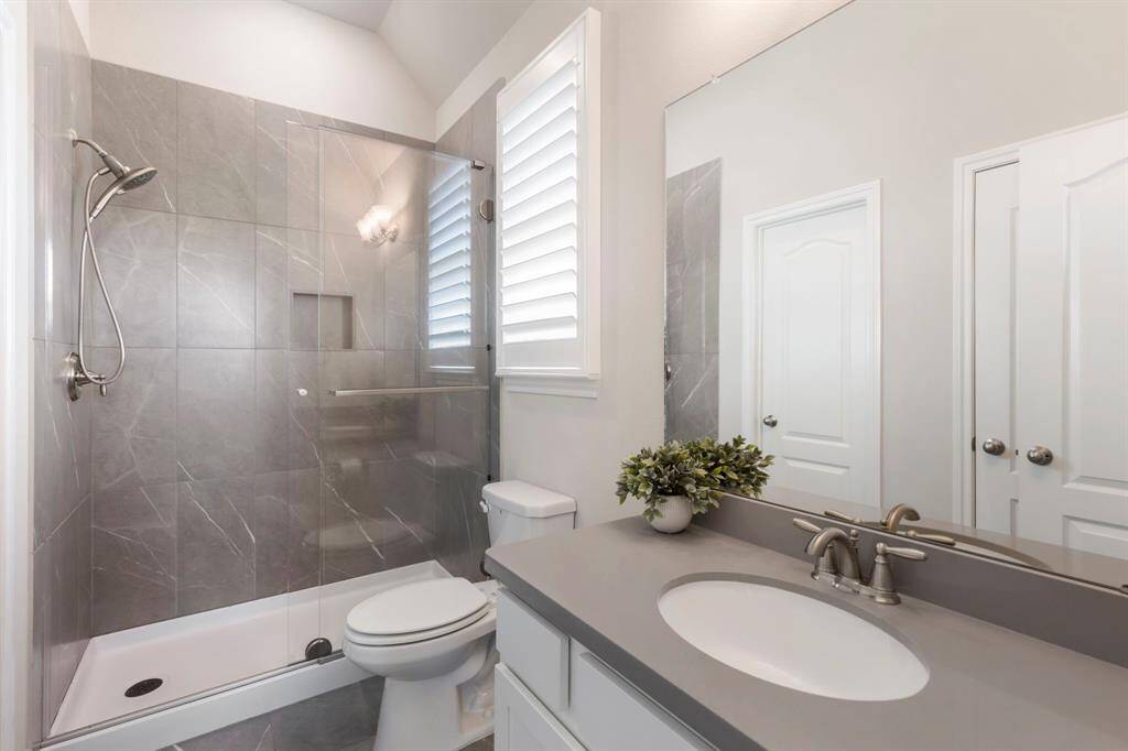 Another beautifully upgraded secondary bath featuring plank-style tile flooring, a high ceiling, a window for natural light, a standalone shower with a sleek frameless track-style sliding door, plus a linen closet and walk-in closet for ample storage!
