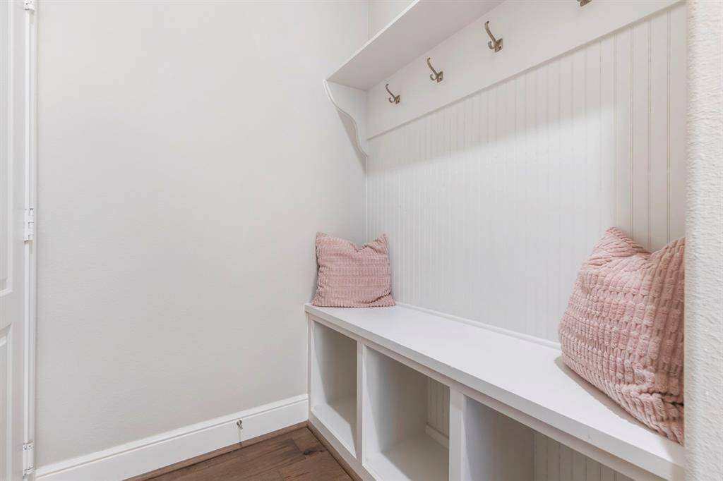 Perfectly located off the garage entry, this well-designed mudroom features a built-in bench, upper and lower storage, hooks for jackets and bags, and a stylish wainscoting accent.