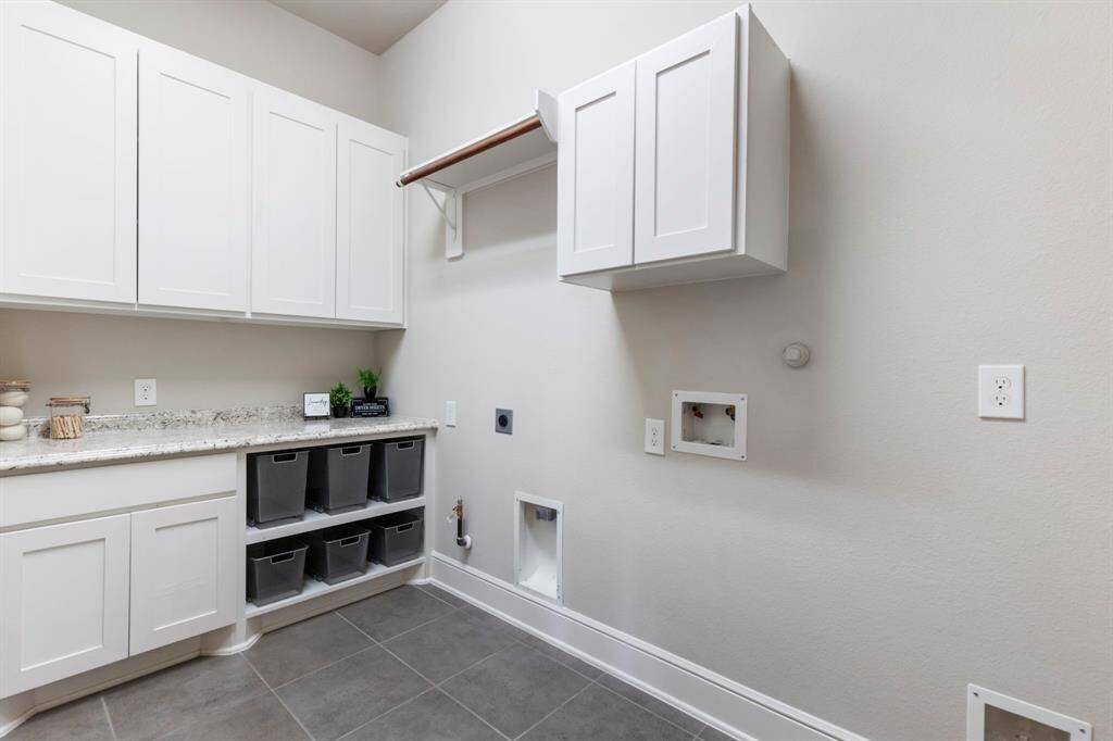 Impressive laundry room with loads of built-ins for storage, mesh basket drawer sliders, granite countertop folding area, clothing rod for drying, room for extra fridge, and pocket door entry - maximizing interior space!