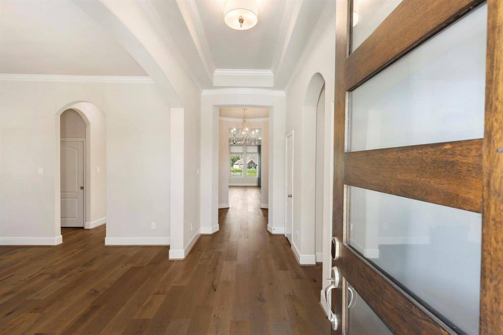 Welcoming entry with beautiful wood flooring, tray ceiling with crown molding, & sightlines extending to the back of the home!
