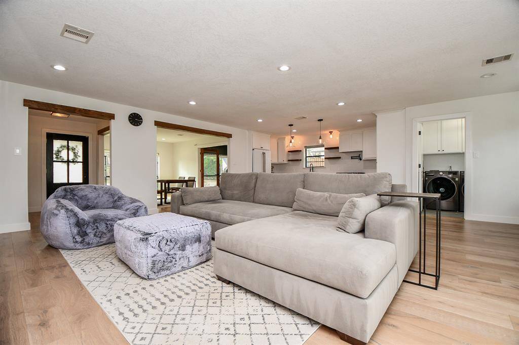 Spacious and inviting living area with an open layout, hardwood floors, and modern lighting, perfect for relaxation and entertaining.