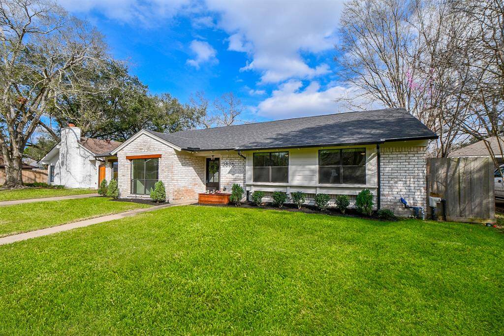 Charming single-story home with beautiful brick exterior, lush lawn, and inviting front porch.