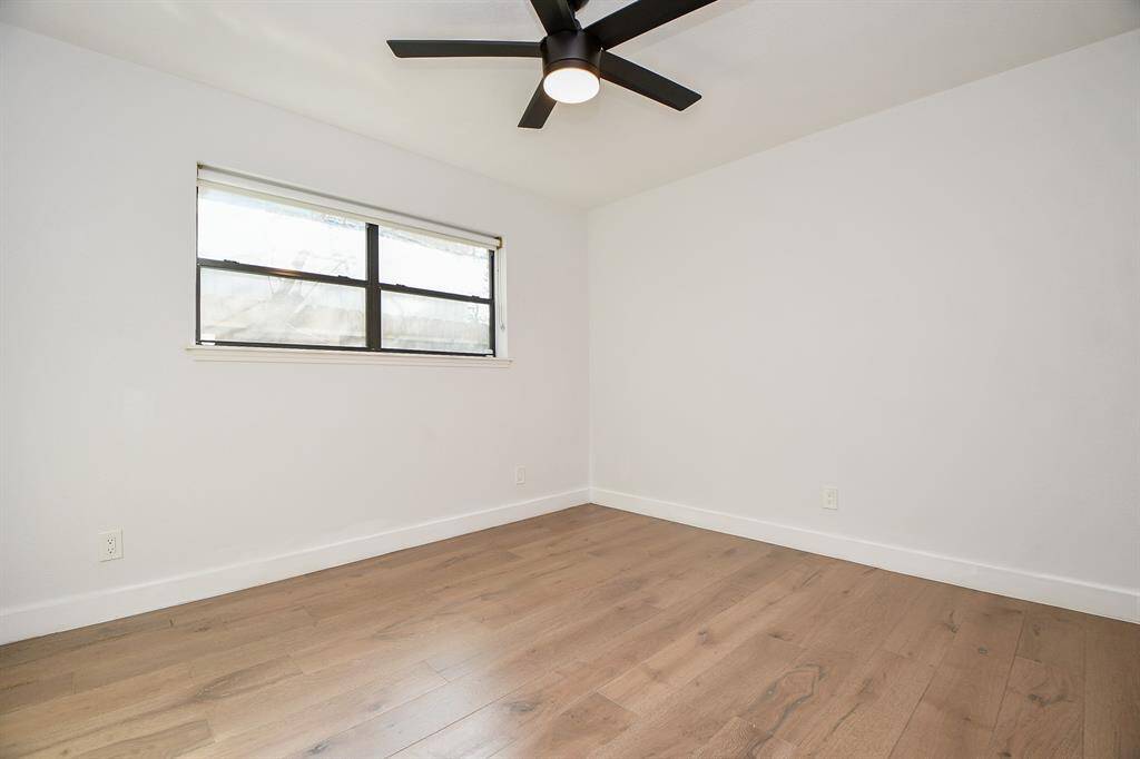 Cozy bedroom featuring sleek hardwood floors, ample natural light, and a modern ceiling fan for comfort and style.