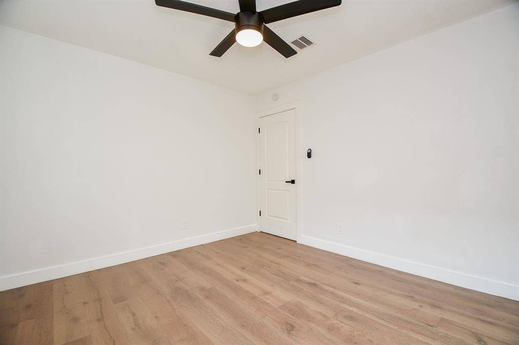 Serene and spacious bedroom featuring elegant hardwood floors and a modern ceiling fan.