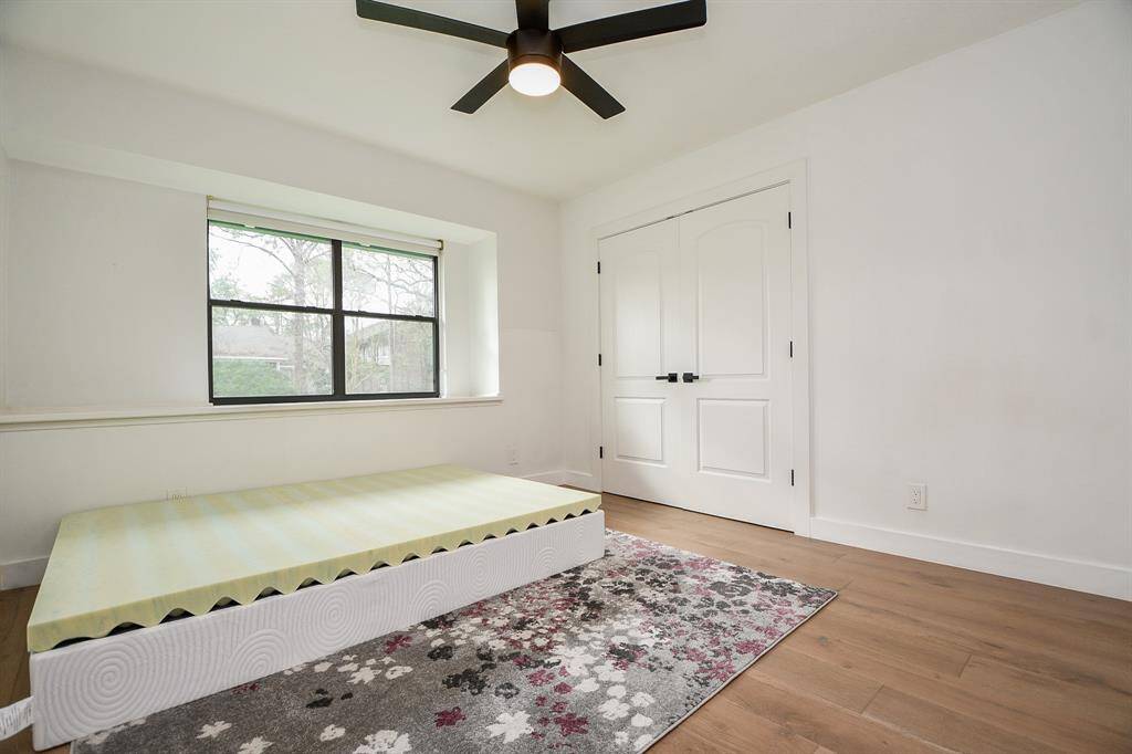 Spacious bedroom featuring large windows for natural light, modern ceiling fan, and ample closet space. Perfect for relaxation and comfort.