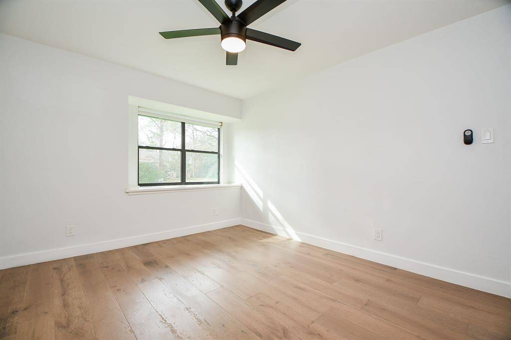 Bright and inviting bedroom with sleek wood floors and a large window offering plenty of natural light.