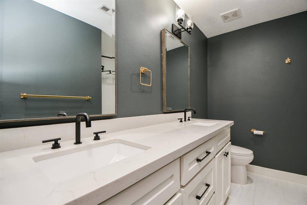 Sleek and modern hall bathroom with dual sinks, elegant fixtures, and ample storage.