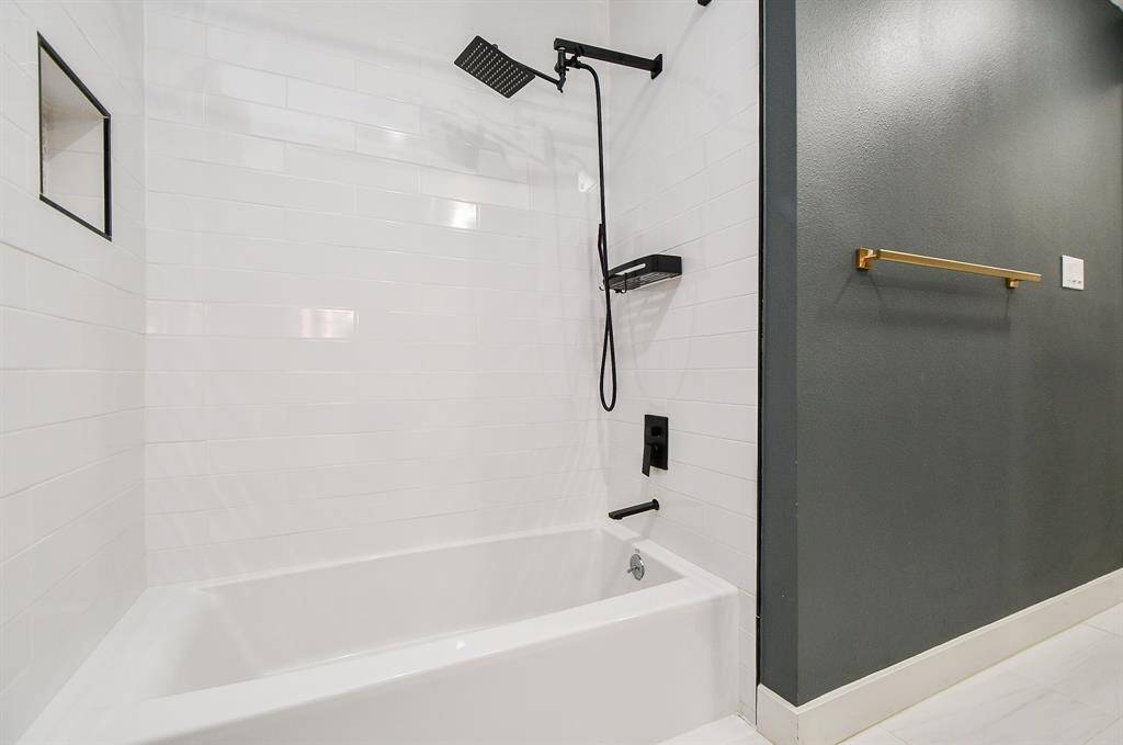 Sleek bathroom featuring a modern rain showerhead, elegant tile backsplash, and chic dark accent wall.