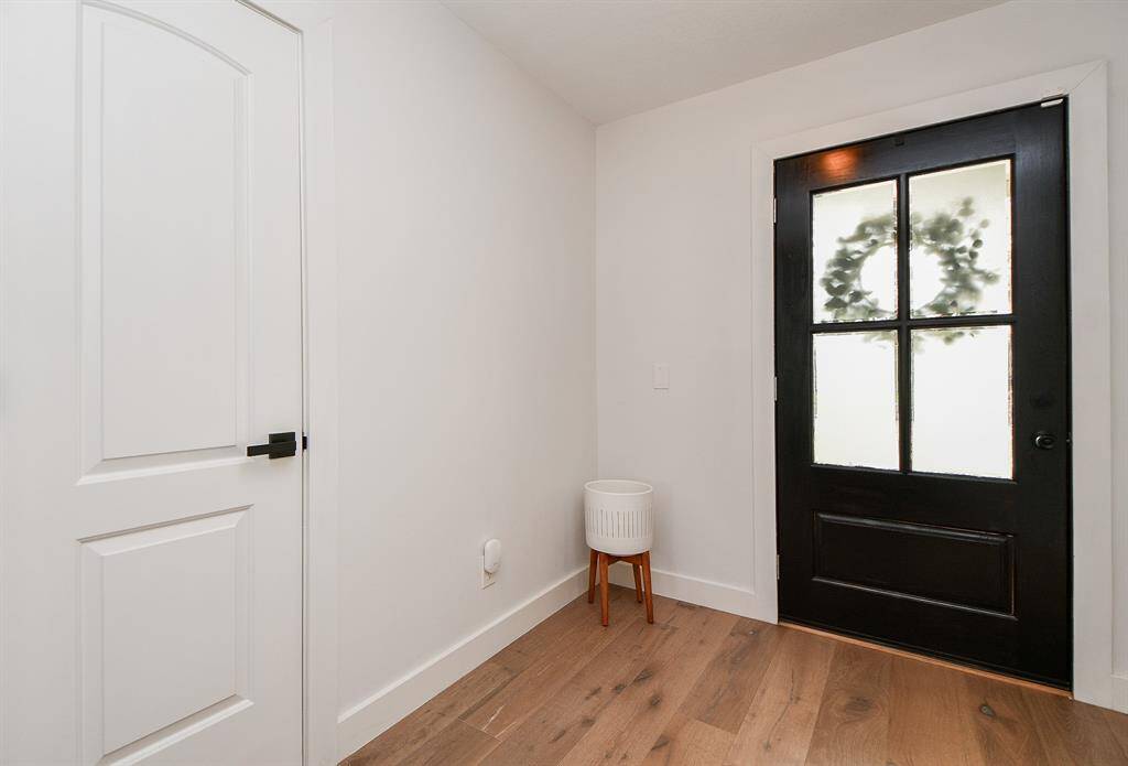 Welcome home to a bright, inviting entryway featuring a sleek black door and warm hardwood floors.