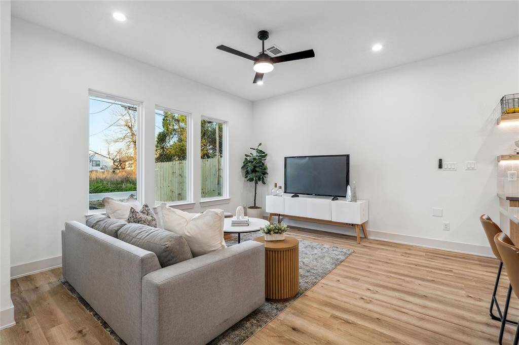 This modern and inviting living room exudes warmth and comfort with huge windows that flood in natural light, offering a stylish and cozy space to unwind and feel at home.