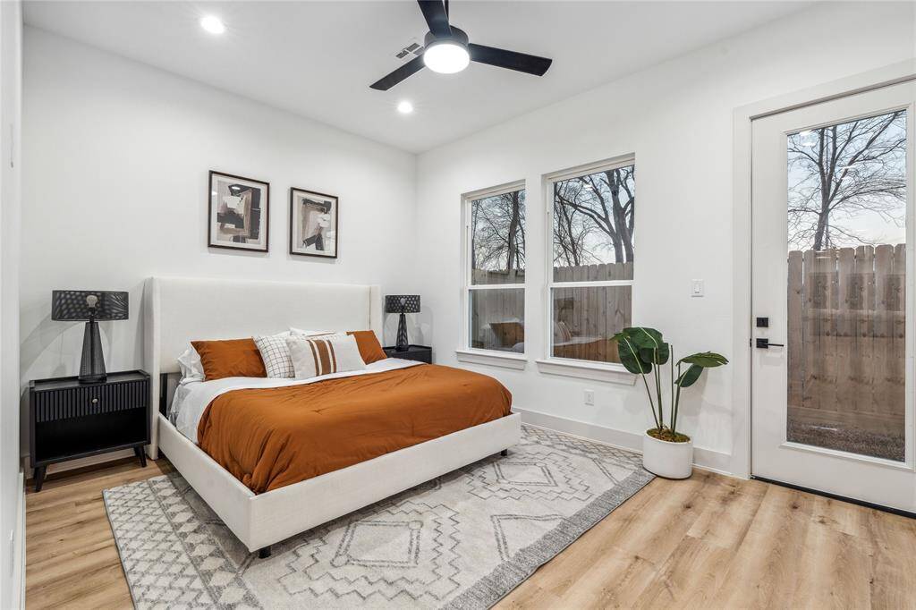 This primary bedroom showcases high ceilings, large windows that invite natural light, and a private outdoor access door, creating a bright and airy retreat.