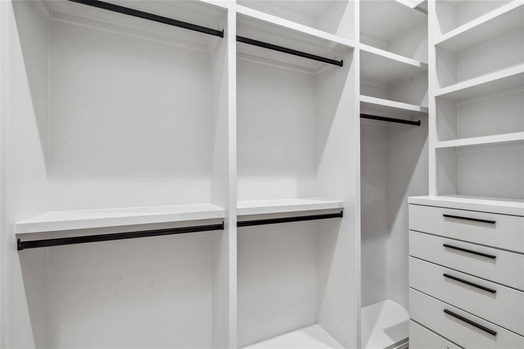 This thoughtfully designed walk-in closet offers a perfect blend of functionality and style, featuring custom shelving, sleek black hardware, and ample storage to keep everything organized and easily accessible.