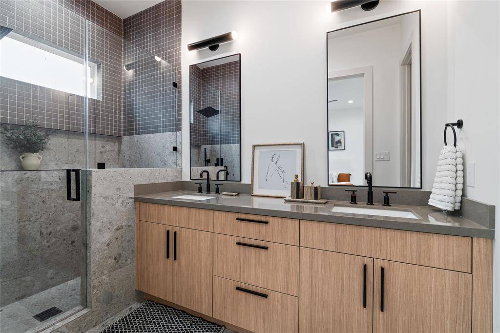 The walk-in shower is elegantly designed with floor-to-ceiling tile, a frameless glass enclosure, and a rainfall showerhead, while strategically placed windows bring in natural light for a spa-like ambiance.
