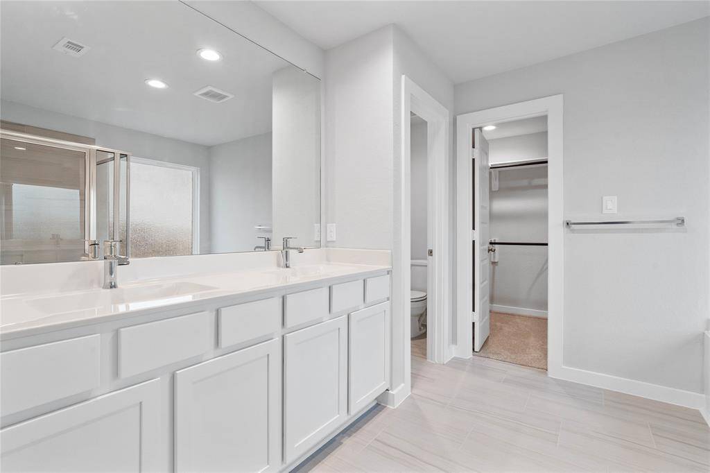 This large primary bath is spacious enough to share! With separate vanities, large closet space, plentiful cabinet and counter space, you are sure to have private area while sharing this bathroom!