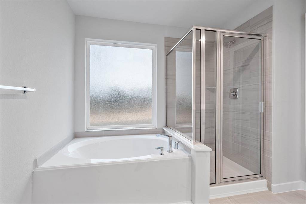 Wow! Look at this primary bathroom! Featuring dark framed walk-in shower with tile surround, separate garden tub for soaking after a long day.