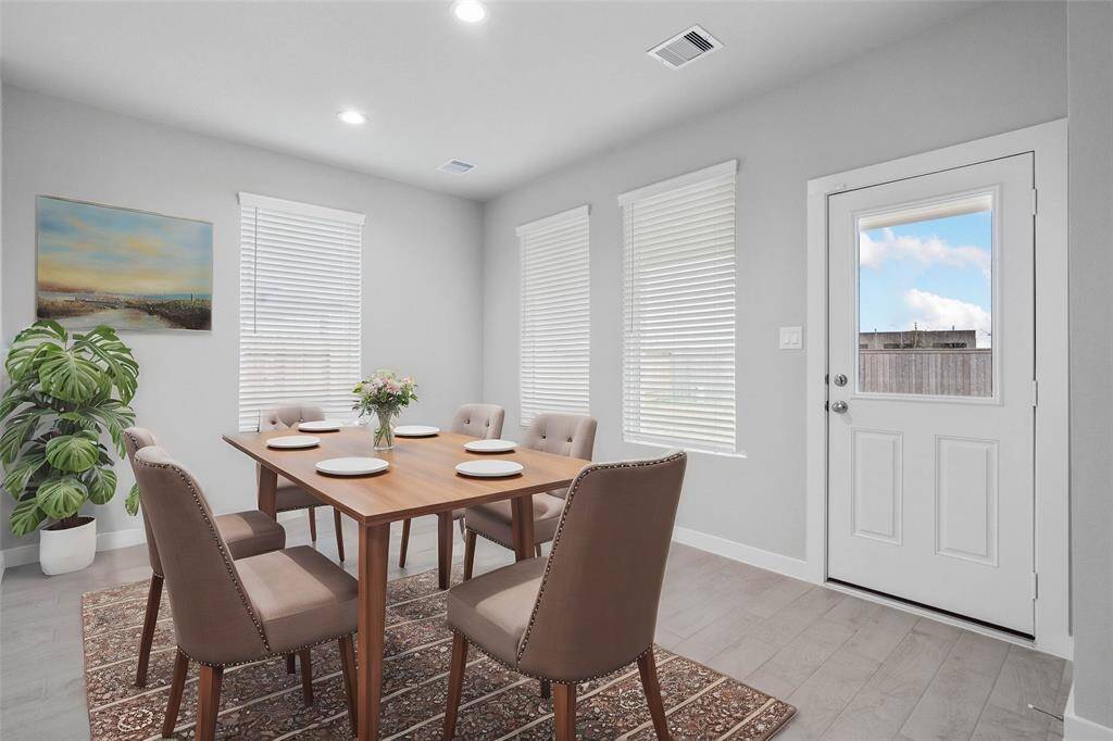 This lovely dining area is perfect for starting the day out on the right foot! This space showcases custom paint, recessed lighting, large windows adding to the ample natural light in the kitchen, and wood look tile flooring!