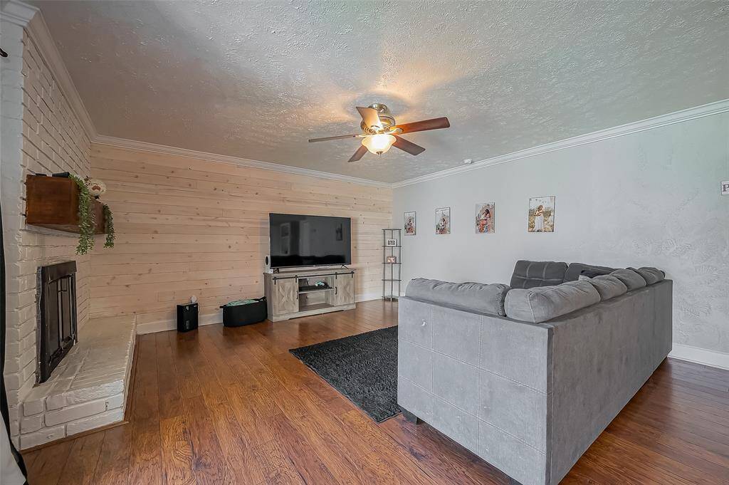 Family room features shiplap accent wall and gas fireplace with wood mantle