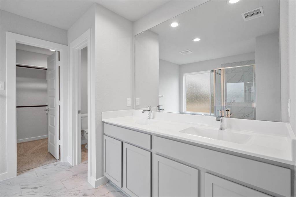 This large primary bath is spacious enough to share! With separate vanities, large closet space, plentiful cabinet and counter space, you are sure to have private area while sharing this bathroom!