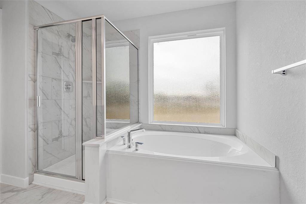 Wow! Look at this primary bathroom! Featuring dark framed walk-in shower with tile surround, separate garden tub for soaking after a long day.