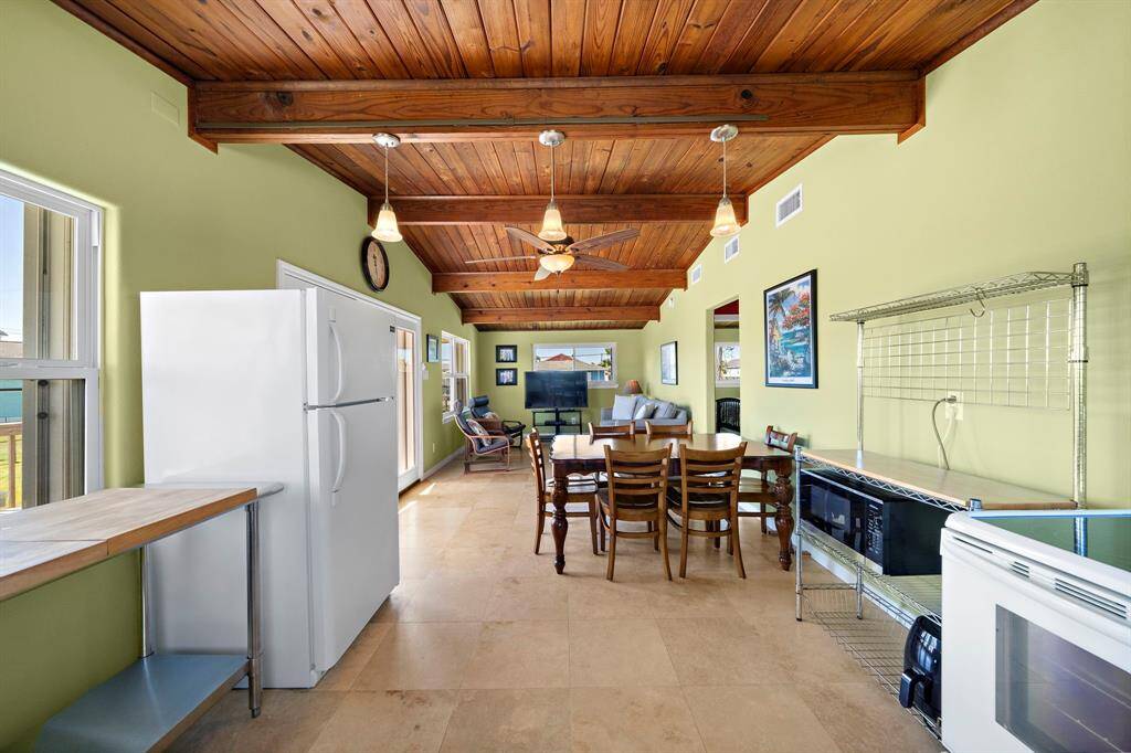 Showcasing clean lines and thoughtful use of space, this kitchen features plenty of prep area, a sink beneath a large window, and durable metal and wood surfaces—perfect for low-maintenance coastal living.
