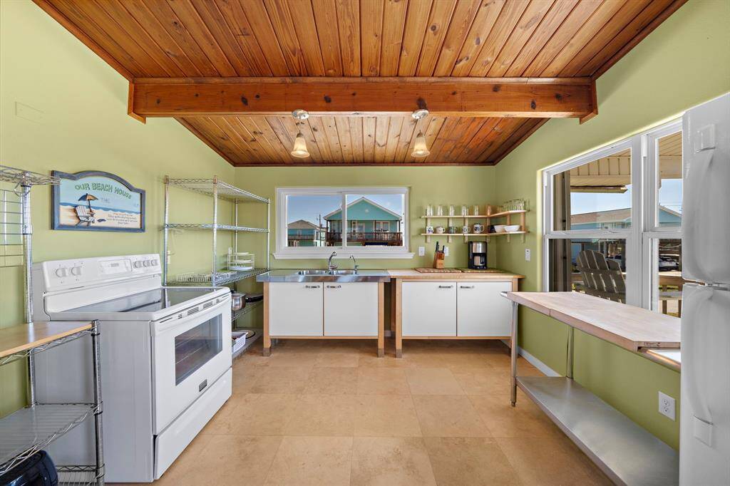 An open living and dining space offers a great flow for entertaining. The wood-beamed ceiling adds character, and large windows bring in tons of natural light. A casual dining table anchors the space across from the kitchen.