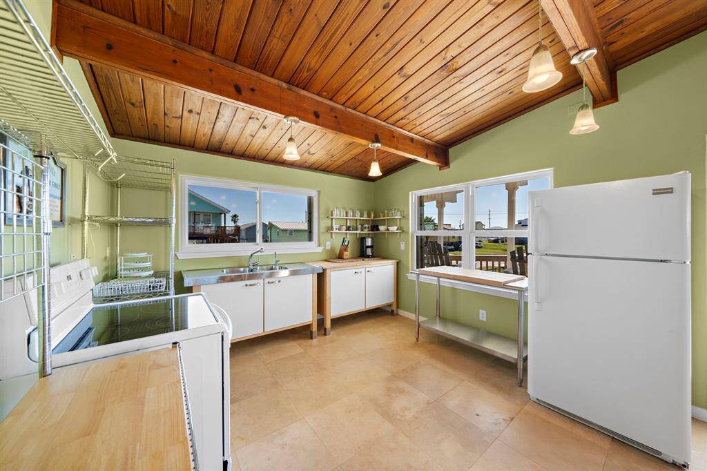 This cheerful kitchen offers stainless steel counters, open shelving, and views out to the front deck. The layout is ideal for easy prep and conversation while cooking.