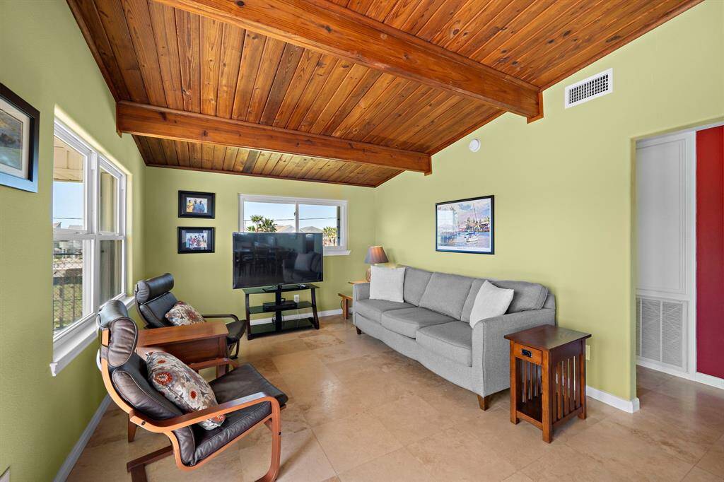 A cozy retreat featuring a beamed ceiling and neutral tile flooring, this space offers great flexibility for relaxing, entertaining, or hosting guests.