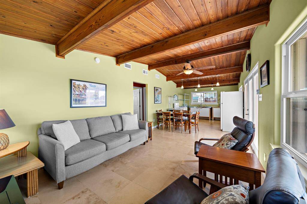 The vaulted wood plank ceiling adds warmth and character to this bright and airy living area, filled with natural light from multiple windows and a glass door leading out to the deck.