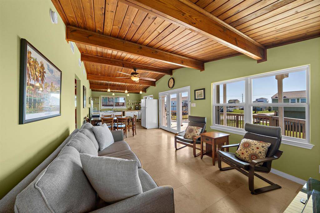 Anchored by a plush gray sofa and comfortable armchairs, the living area offers a cozy place to unwind. With views out every window and a direct line to the kitchen and dining area, it’s the heart of the home.