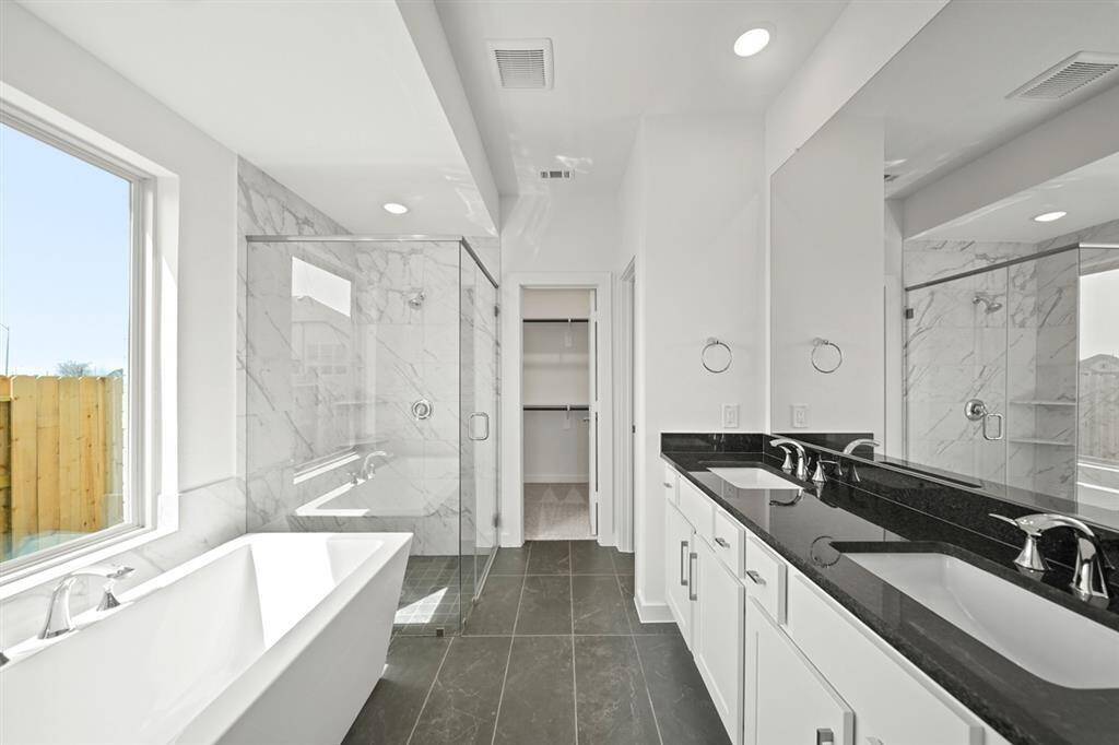 Unwind in your new luxurious primary bath, featuring beautiful free standing tub and separate glass-enclosed shower with floor to ceiling tile accents.