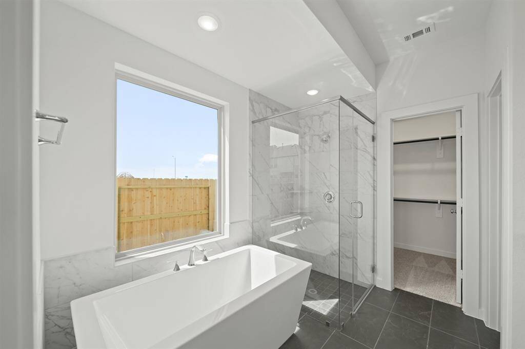 Unwind in your new luxurious primary bath, featuring beautiful free standing tub and separate glass-enclosed shower with floor to ceiling tile accents.